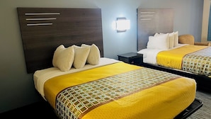 A hotel room with two beds, each with a headboard, a bedside table, and a lamp. - Garden Inn and Suites Little Rock (Little Rock)