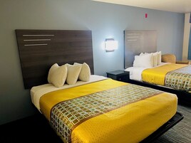 Habitación de hotel con dos camas, cada una con cabecero, mesita de noche y lámpara.