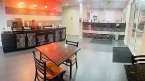 A modern kitchen with a marble countertop, a dining area with a marble table and chairs, and a reception area with a marble counter and pendant lighting. - Garden Inn and Suites Little Rock (Little Rock)