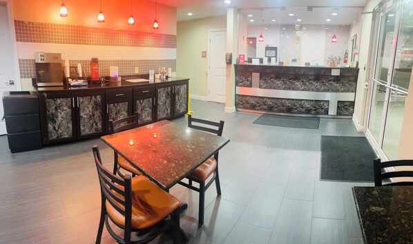 A modern kitchen with a marble countertop, a dining area with a marble table and chairs, and a reception area with a marble counter and pendant lighting. - Garden Inn and Suites Little Rock (Little Rock)