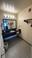 Un baño con un lavamanos negro, un espejo y un perchero para toallas.