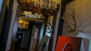 Un gran candelabro, un espejo y un cuadro en una habitación con un banco de madera.