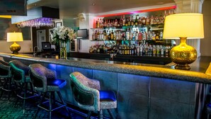 Zona de bar con barra, taburetes y una variedad de botellas.