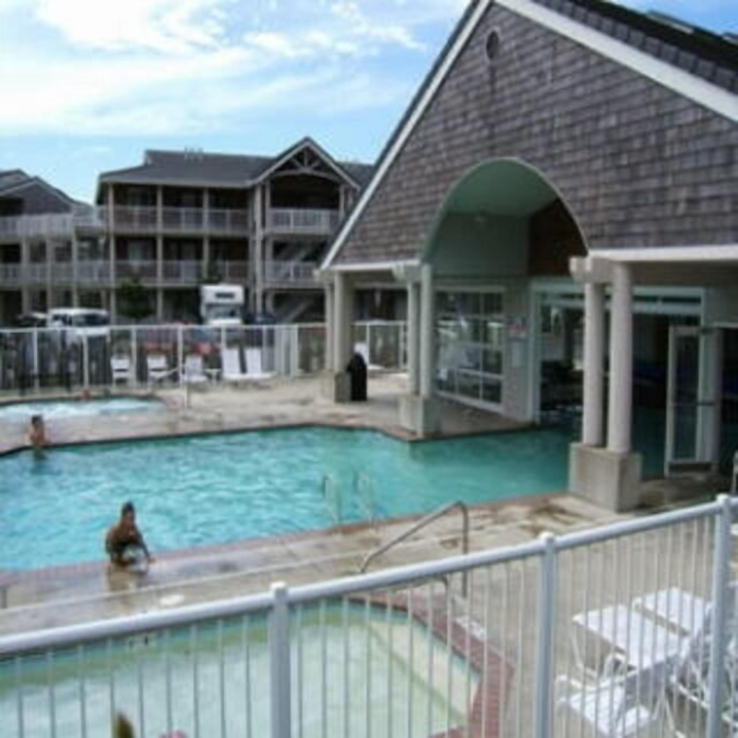 A swimming pool with a fenced deck, surrounded by multi-story buildings with balconies.