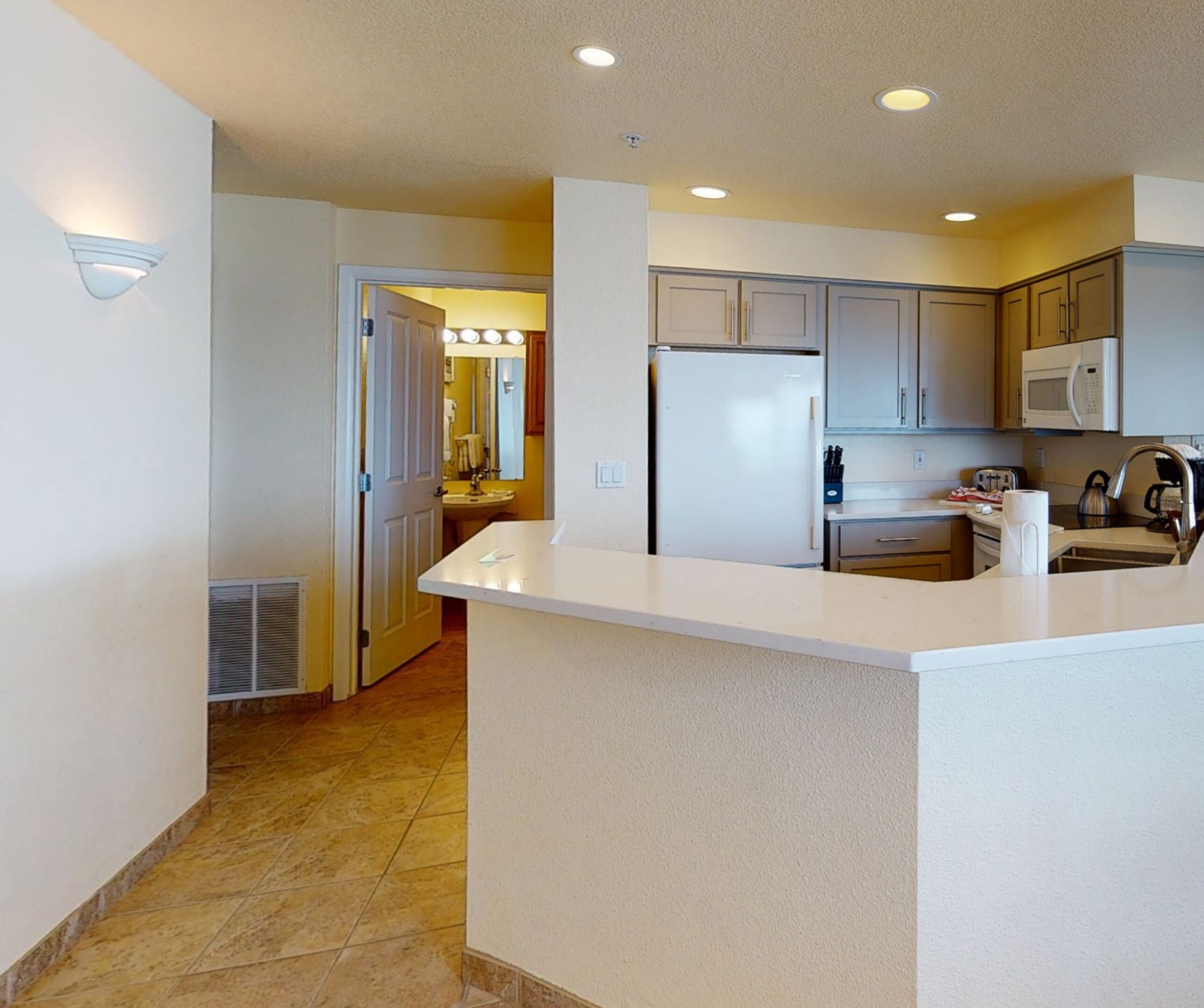 A modern kitchen with a central island, stainless steel appliances, and a microwave.