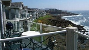 Um imóvel costeiro com varanda e vista para o mar, com mesa e cadeiras.