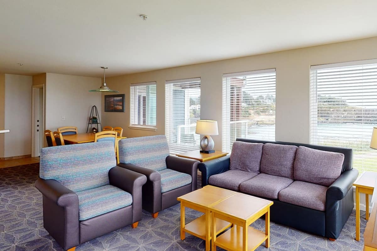A living room with a sofa, two armchairs, a coffee table, and a dining table with chairs.