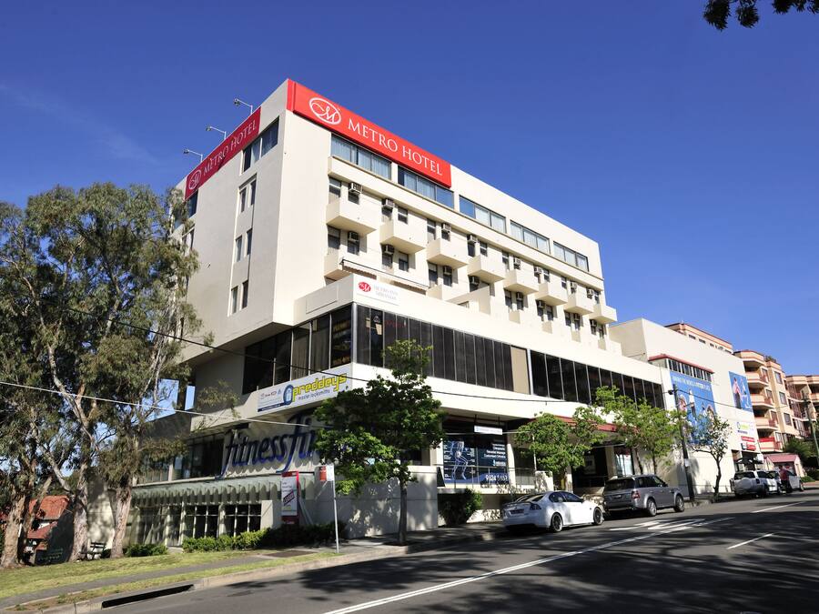 Un hotel con un llamativo letrero rojo, varios pisos y un diseño arquitectónico moderno.