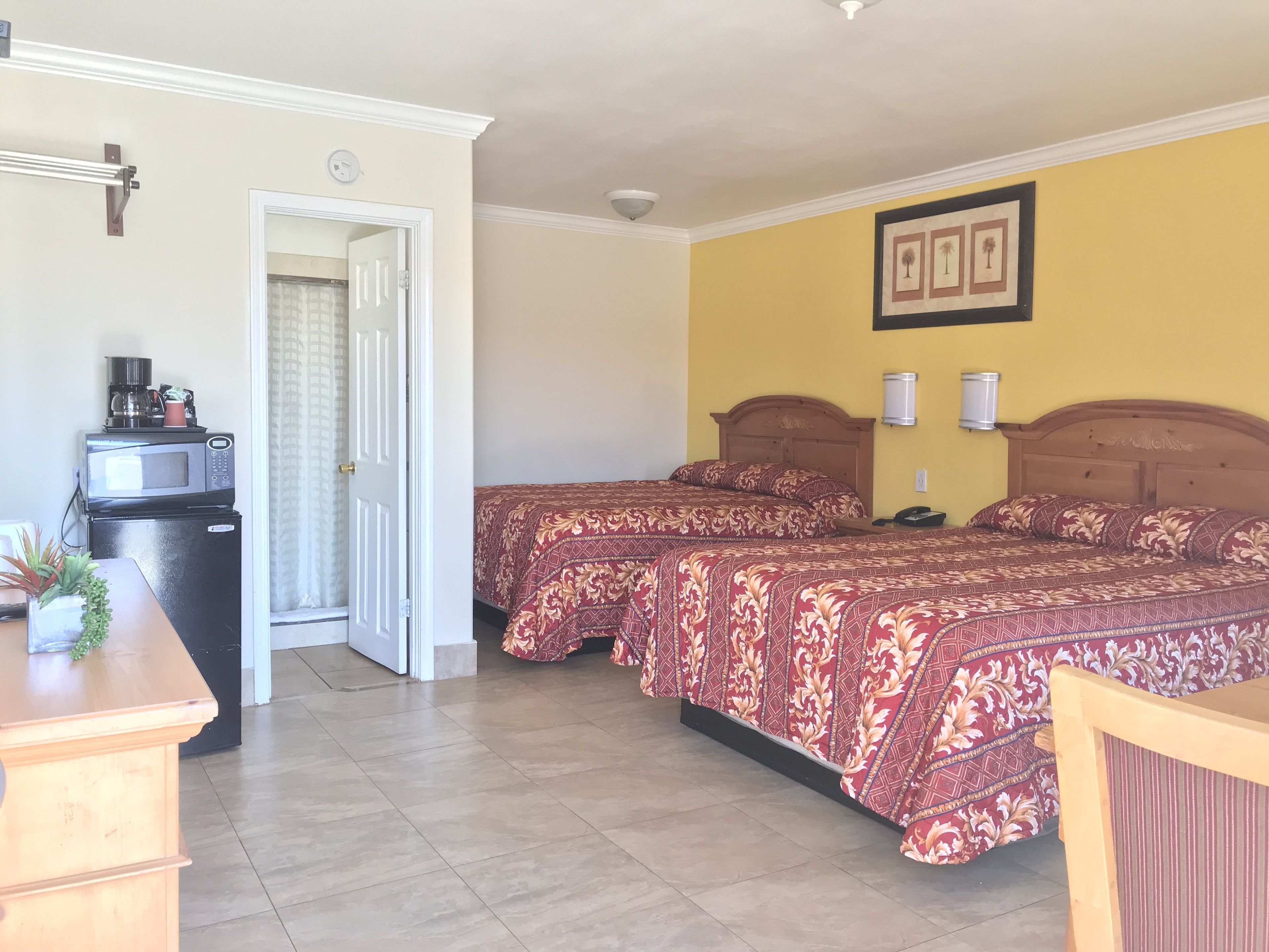 Una habitación de hotel con cama, escritorio, microondas y refrigerador.