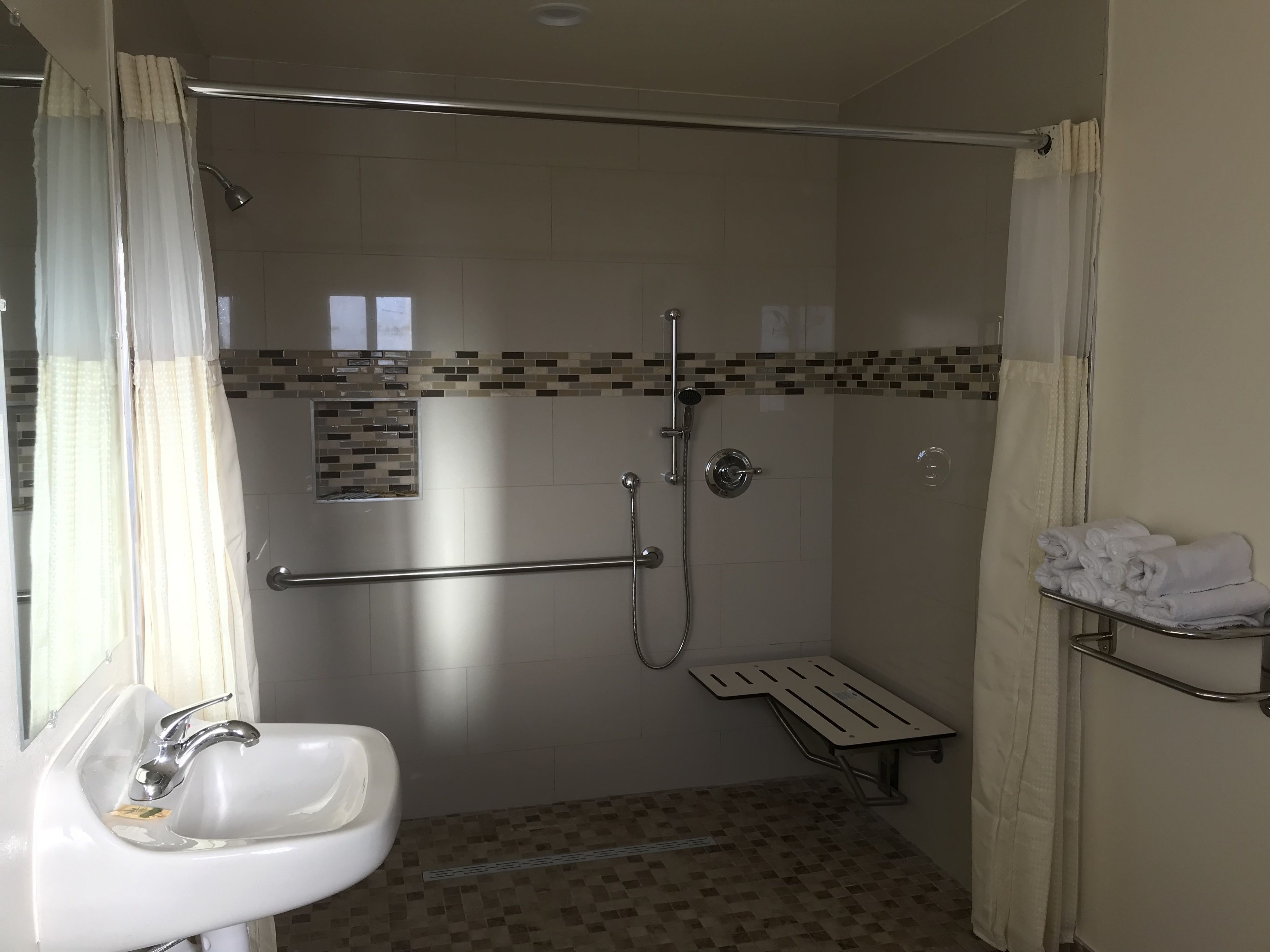 A bathroom with a shower, a sink, and a towel rack.