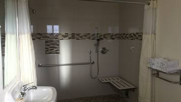 A bathroom with a shower, a sink, and a towel rack.