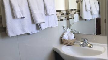 A bathroom with white towels hanging on a rack, a sink with a chrome faucet, and a mirror above the sink.