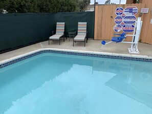 A swimming pool with lounge chairs and a lifeguard stand.
