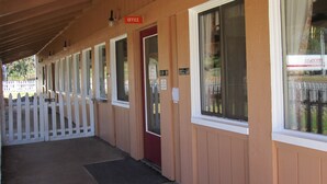 A row of rooms with white picket fences, a red door labeled "Office", and a window with a sign that says "Thank you for not smoking". - Rancho California Inn (Temecula)
