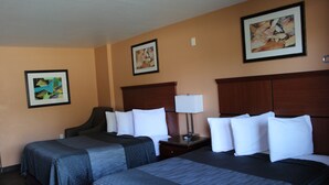 A hotel room with two beds, a wooden headboard, a nightstand with a lamp, and framed artwork on the walls. - Rancho California Inn (Temecula)