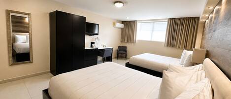 A hotel room with two beds, a desk, a chair, a TV, and a large mirror.
