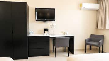 Ein Hotelzimmer mit einem Bett, einem Schreibtisch mit Stuhl, einem Fernseher, einer Klimaanlage und einem Kleiderschrank.