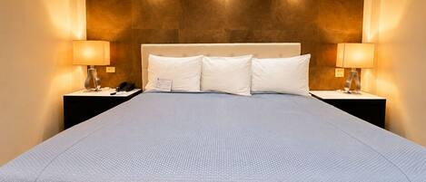Habitación de hotel con una cama grande, dos mesitas de noche, una lámpara de pared y un teléfono.