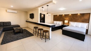 Une chambre d’hôtel moderne équipée d’un canapé, d’une petite table, d’un coin bar et d’un lit.