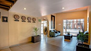 Un hall d’entrée spacieux au design moderne, comprenant un comptoir d’accueil, un espace salon et une grande fenêtre donnant sur la rue.