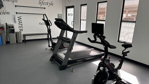 Une salle de sport équipée de tapis de course, d’un vélo elliptique et d’un vélo d’appartement.
