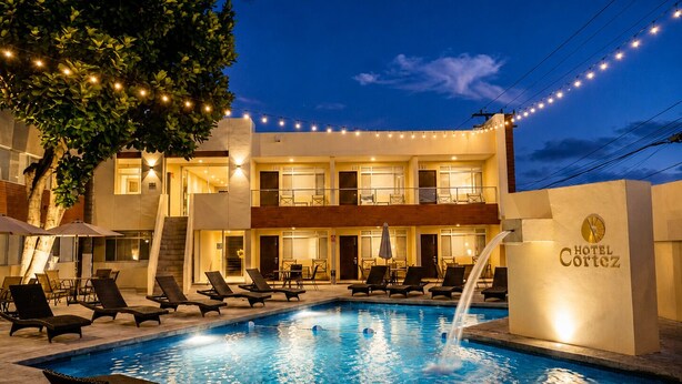 Un hôtel doté d’une piscine, de chaises longues et de guirlandes lumineuses.