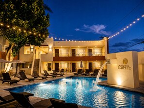 A hotel with a swimming pool, lounge chairs, and string lights. - Hotel Cortez Baja Inn – Ensenada (Ensenada)