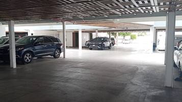 Ein überdachter Parkbereich mit mehreren Fahrzeugen, darunter SUVs, und einem Betonboden.