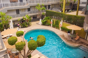 A swimming pool with a curved edge, surrounded by lounge chairs and umbrellas, and a staircase leading to an upper level. - Baja Inn Hoteles La Mesa (Tijuana)