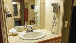 A bathroom with a sink, mirror, and hair dryer mounted on the wall. - Baja Inn Hoteles La Mesa (Tijuana)