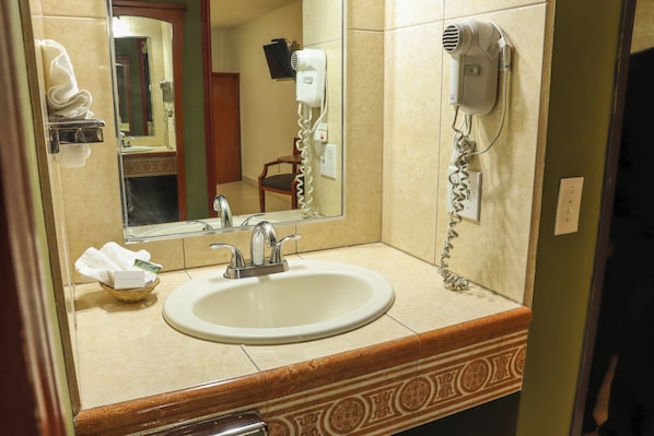 Bathroom features a large mirror, hairdryer, and a sink with modern faucet.