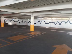 Park your car in designated spaces with clear directional arrows on the floor, surrounded by distinctive zigzag-patterned walls and pillars with yellow bases.