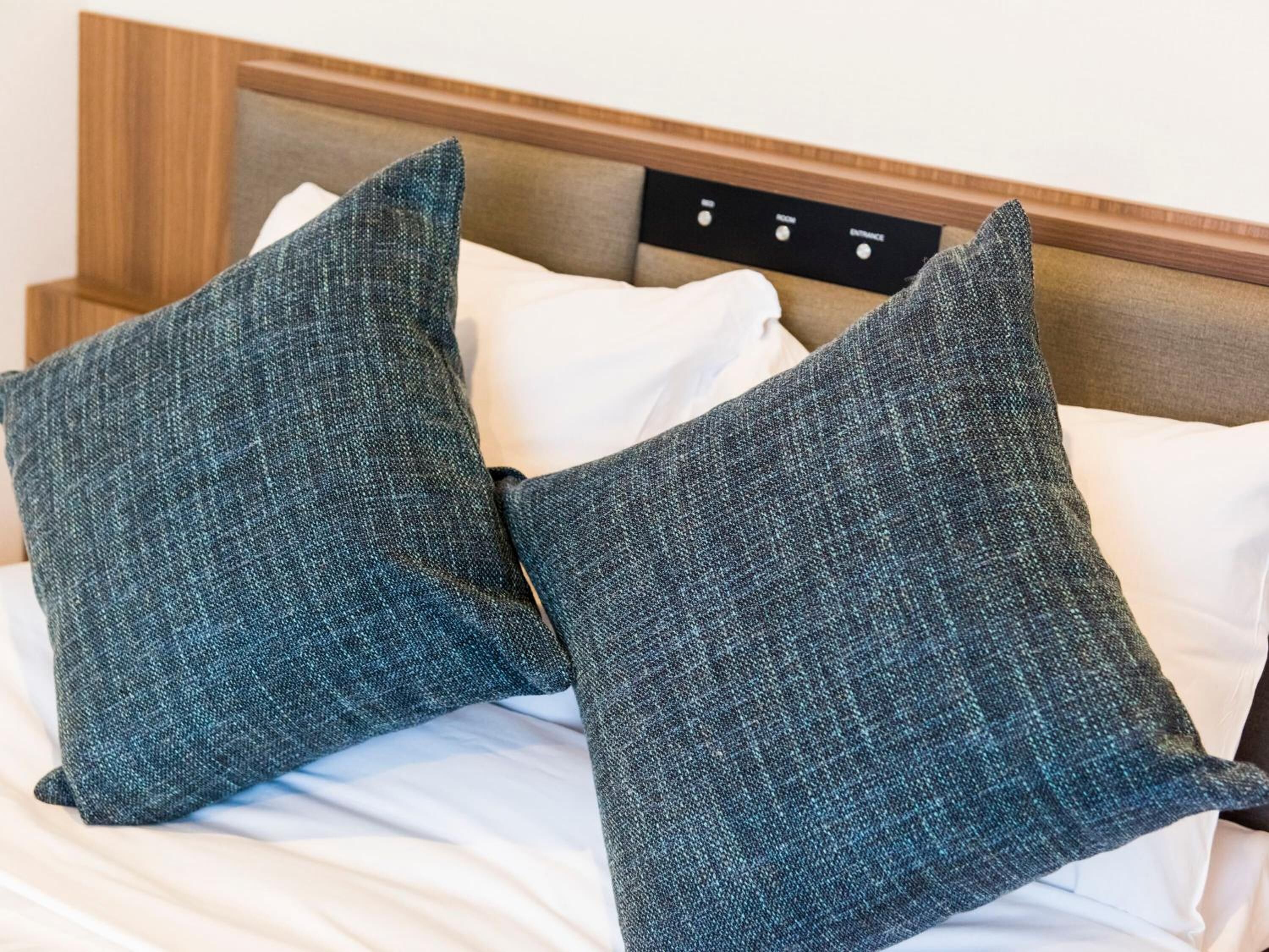 A bed with two square pillows and a wooden headboard.