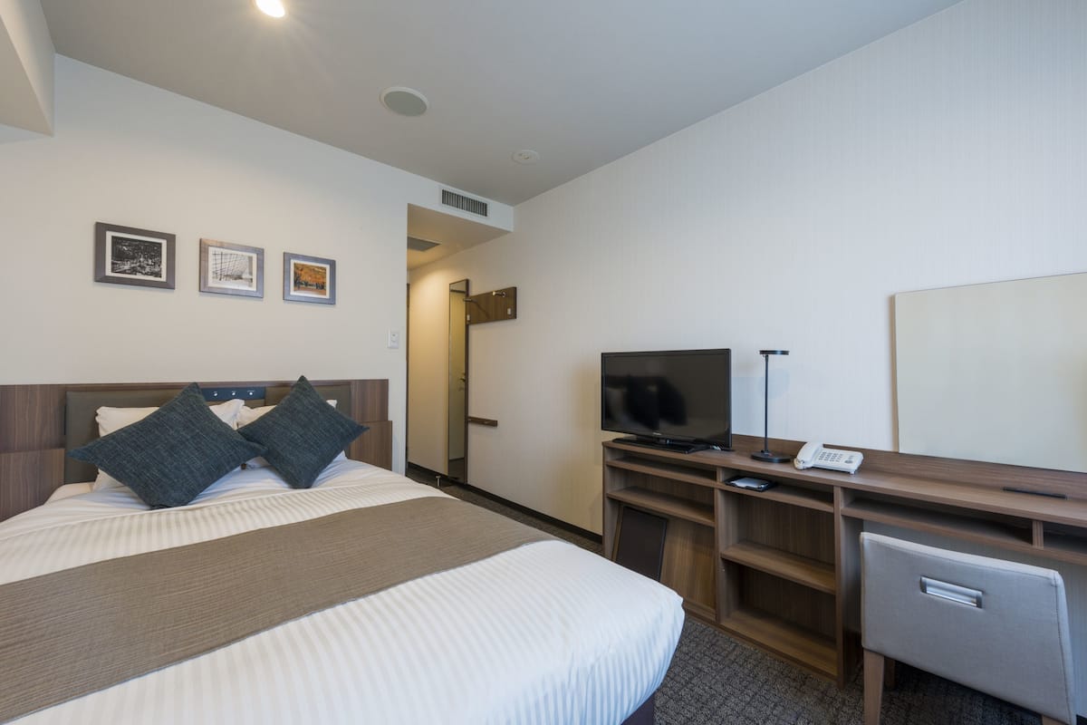 Ein Hotelzimmer mit einem Bett, einem Schreibtisch, einem Fernseher und einem kleinen Kühlschrank.