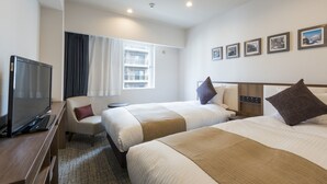 Habitación de hotel con dos camas, televisor, escritorio y ventana con cortinas.