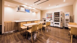 Un restaurante moderno con mesas y sillas de madera, una barra y máquinas expendedoras.