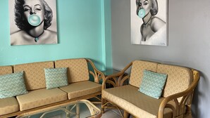 Quarto com dois sofás de vime, uma mesa de centro de vidro e paredes verde-água.