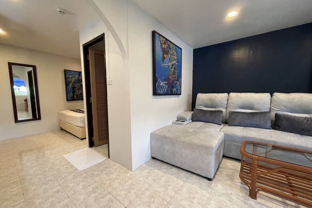A modern living room with a sectional sofa, a glass coffee table, and a large painting on the wall.