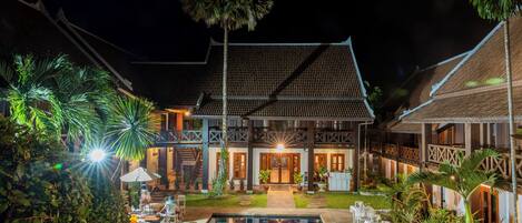 A poolside area with a pool, lounge chairs, and a building with a traditional design.