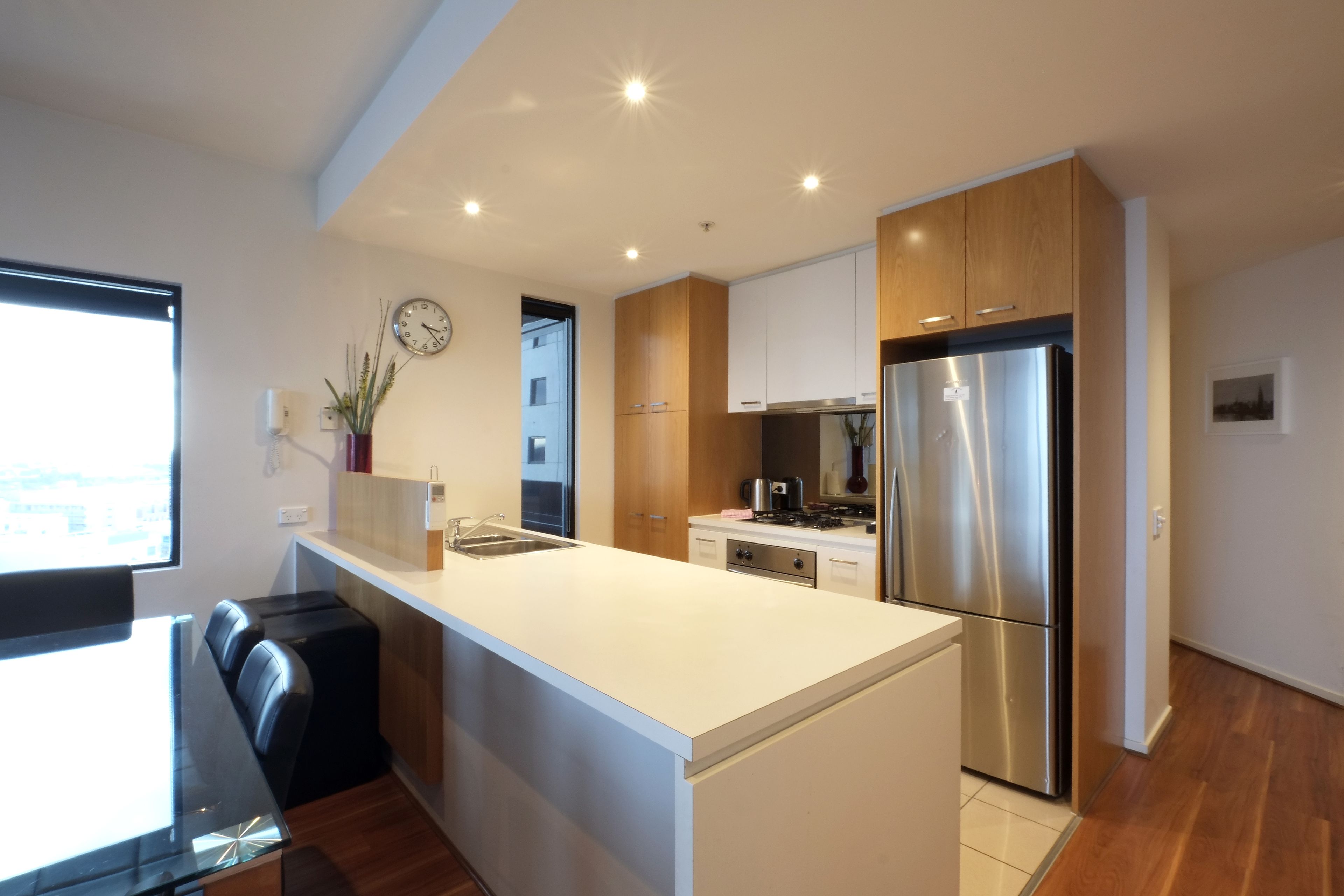 A modern kitchen with a central island, stainless steel appliances, and wooden cabinetry.