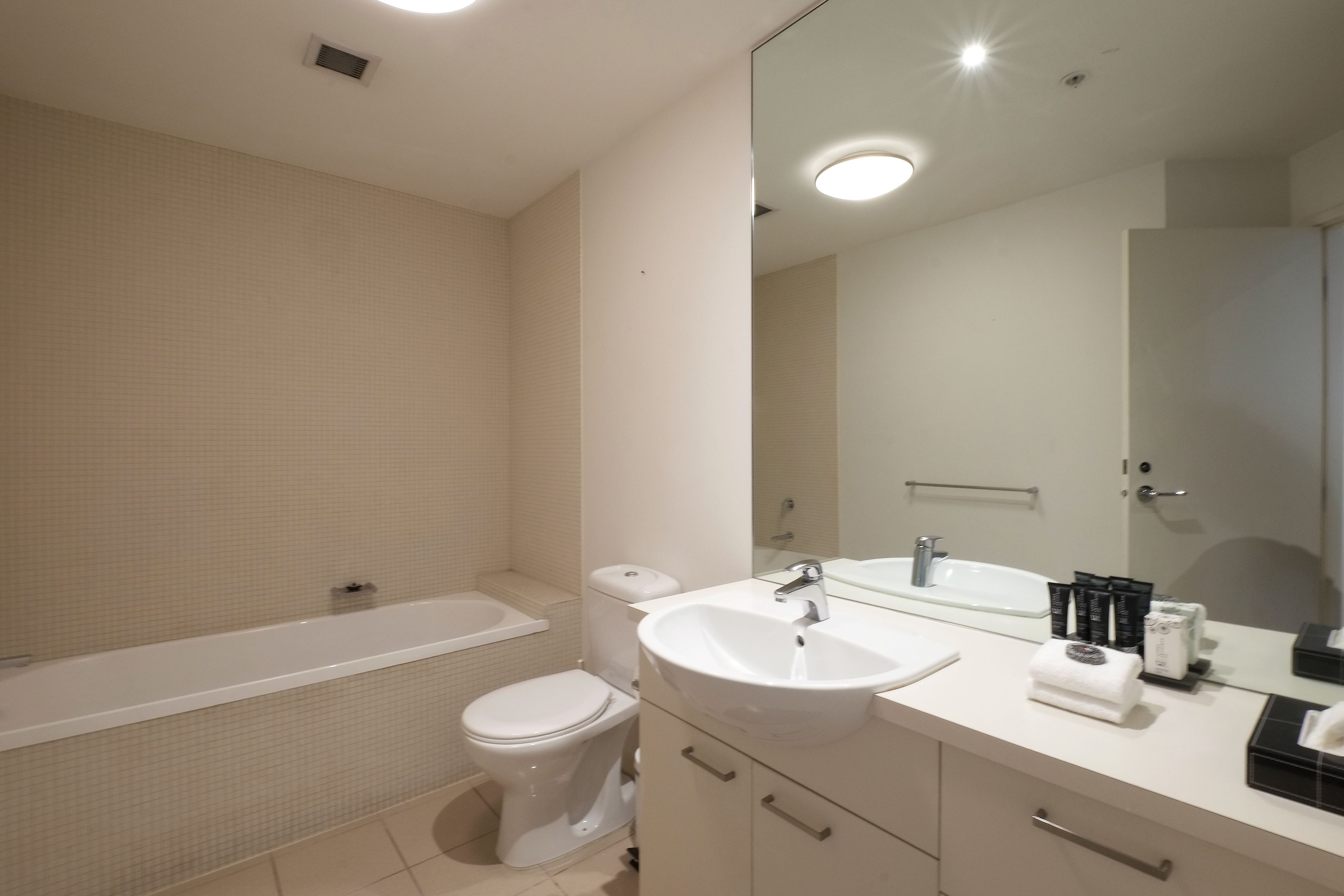 A modern bathroom with a bathtub, toilet, sink, and mirror.