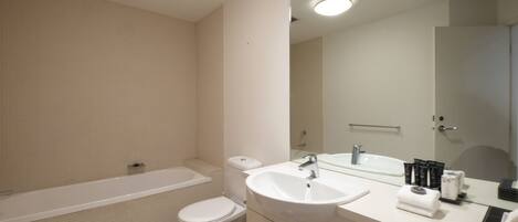 A modern bathroom with a bathtub, toilet, sink, and mirror.