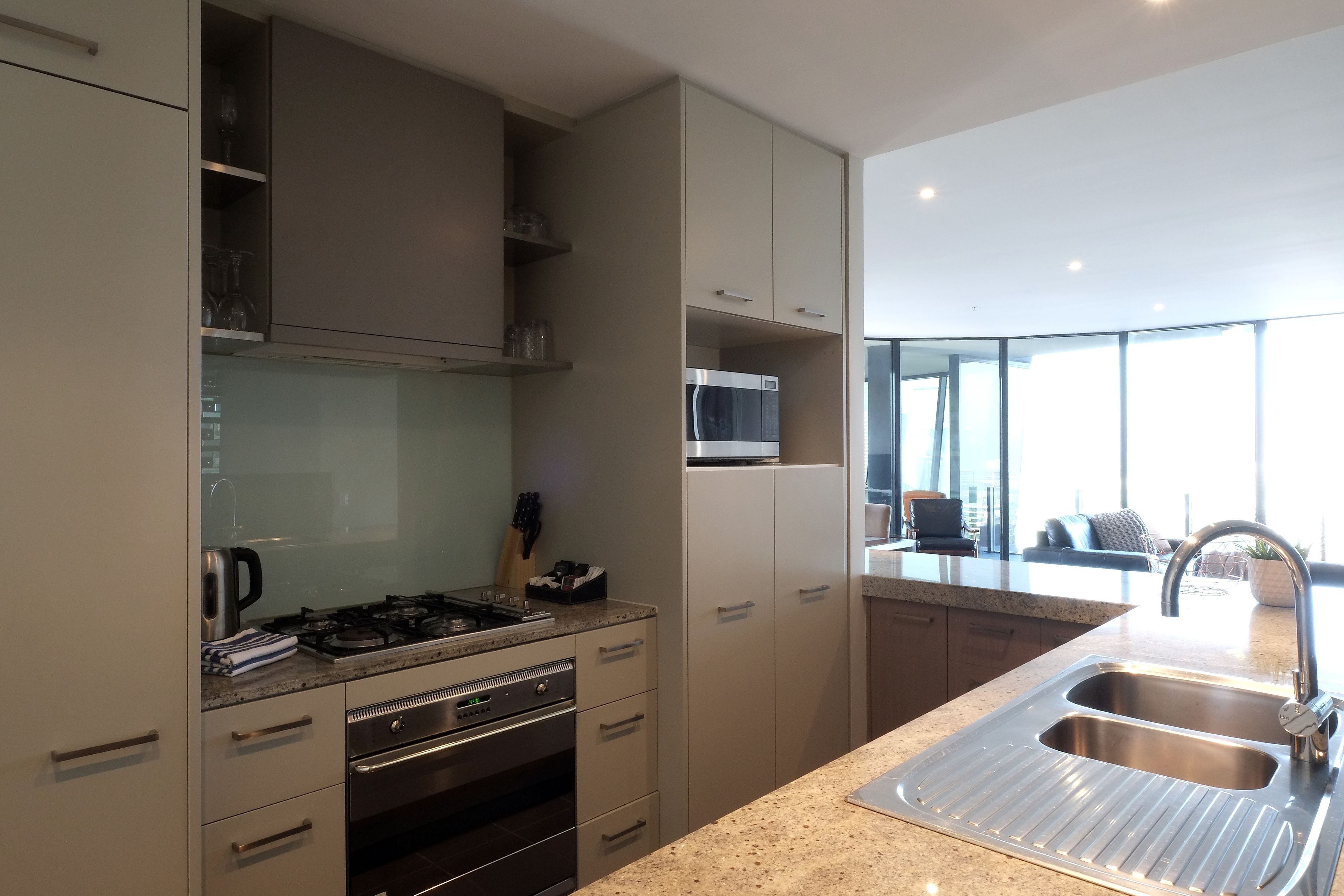 A modern kitchen with stainless steel appliances, a granite countertop, and a large window providing natural light.