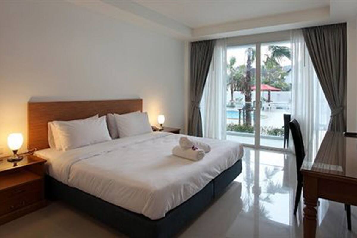 A hotel room with a large bed, a desk, and a TV.