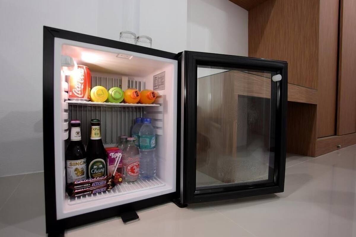 A mini-fridge with a black frame, containing various beverages and snacks.