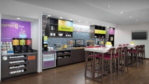 A modern coffee shop with a counter, bar stools, and a variety of coffee and tea options.