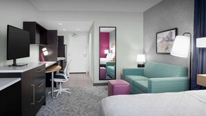 A modern hotel room with a bed, desk, chair, and a large mirror.