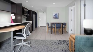 A modern kitchen with dark cabinetry, a microwave, and a small dining area with a table and chairs.