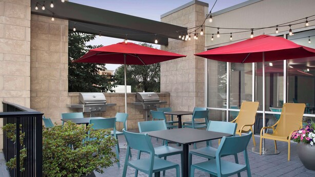 An outdoor patio with seating, a grill, and string lights.