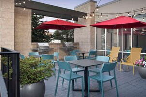Un patio al aire libre con asientos, una parrilla y luces colgantes.